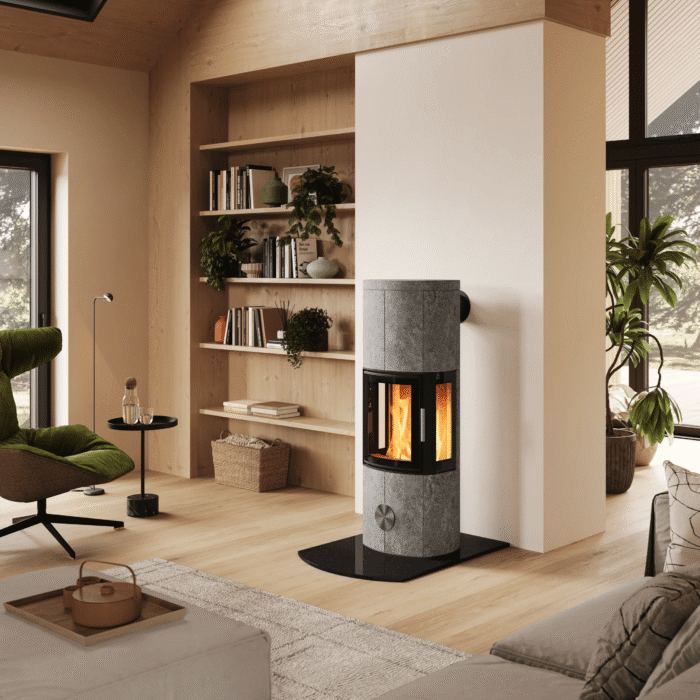 Una stufa pietra ollare moderna collocata al centro di un interno scandinavo luminoso, con scala in legno, zona salotto e servizio da caffè in primo piano.
